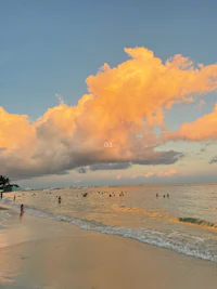 a beach at sunset with people swimming in the water